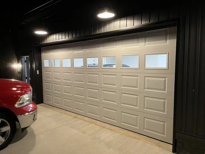 Completed Blackstone installation showing a white sectional garage door with upper windows inside a dark garage