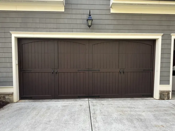 Completed Blackstone installation with a dark brown raised-panel double garage door beneath a covered entry