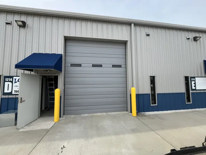 Completed Blackstone installation showing a white sectional garage door beside a pedestrian door on a light exterior