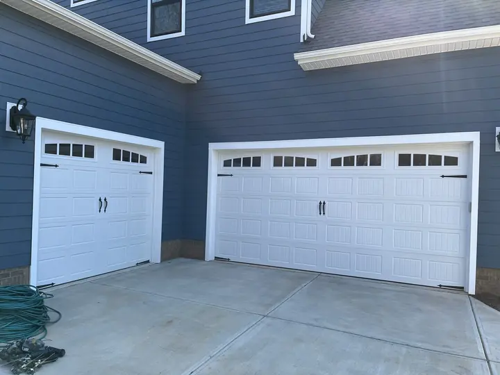Completed Blackstone Wooden Garage Door installation with a vertical natural-wood-finish door on a dark structure