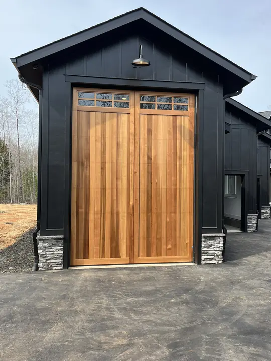 Completed Blackstone installation with two white garage doors and upper windows on a two-story exterior