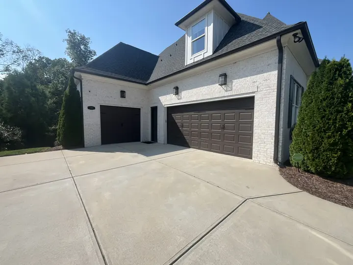 Completed Blackstone installation with black double garage doors on a white home with dormers