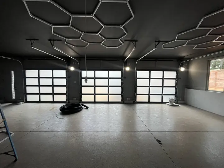 Completed Blackstone Glass Garage Door installation inside a dark high-ceiling space