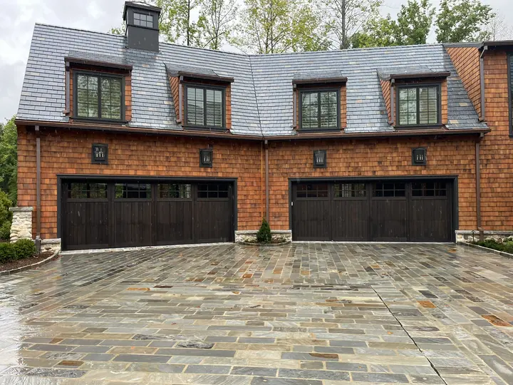 Completed Blackstone custom garage door installation with two dark garage doors on a brick exterior