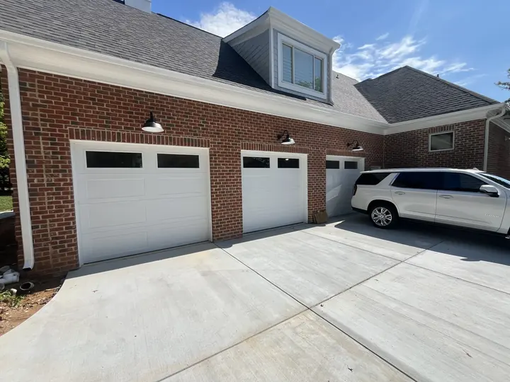 Completed Blackstone custom garage door installation with white garage doors on a brick residential exterior