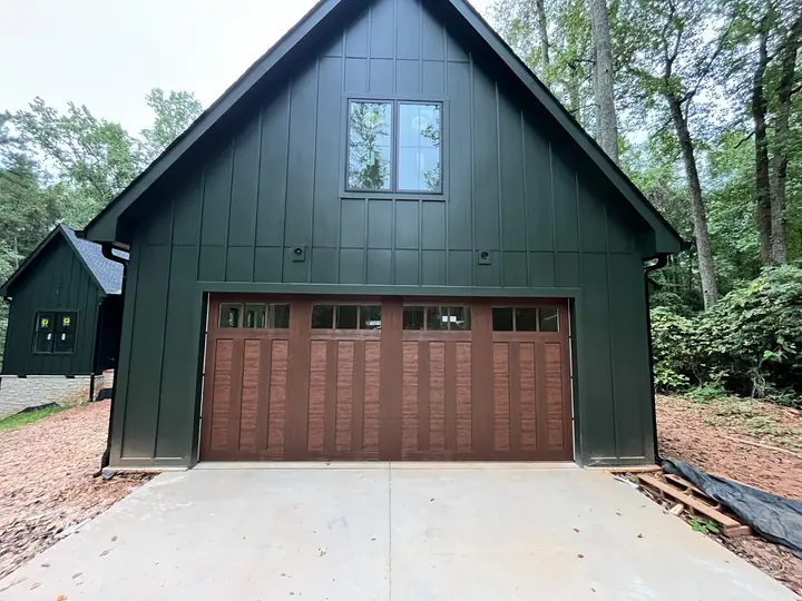Completed Blackstone installation with a brown garage door on a forest-green barn-style exterior