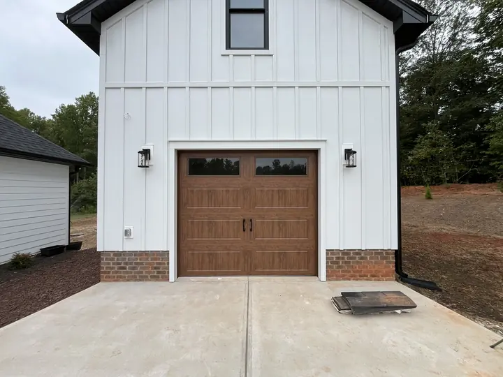 Completed Blackstone installation with a brown single garage door on a white barn-style exterior