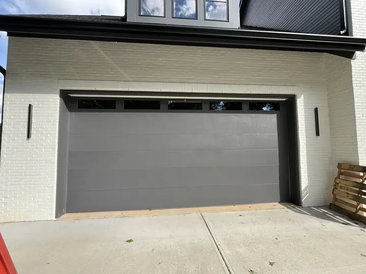 Completed Blackstone installation with a white sectional garage door on a white exterior