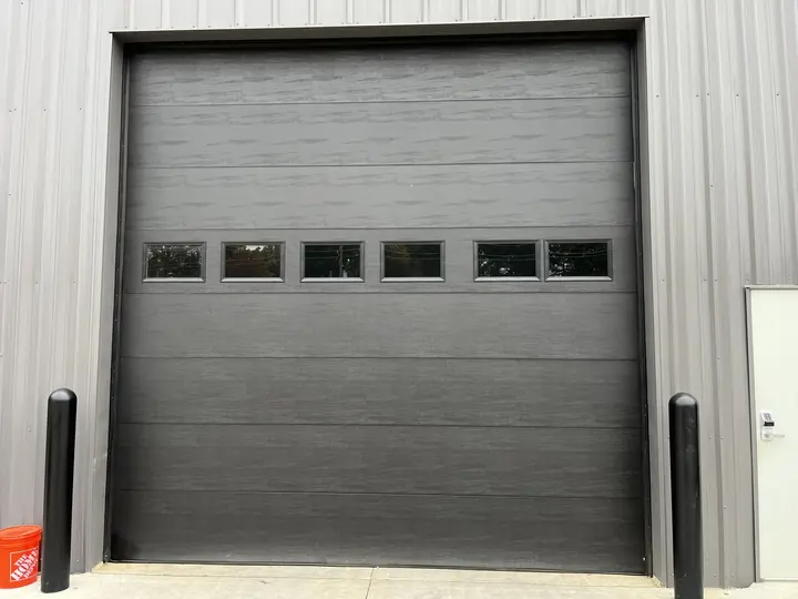 Completed Blackstone installation with a gray sectional garage door on a light exterior