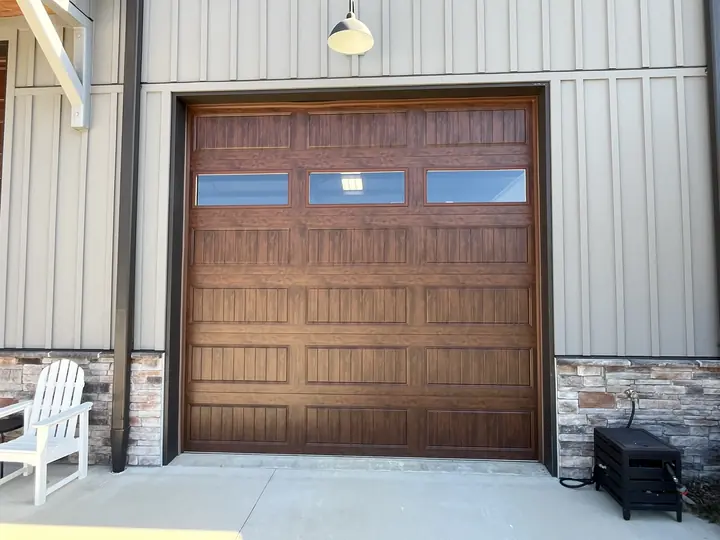 Completed Blackstone installation with a brown garage door and upper windows on a gray outbuilding