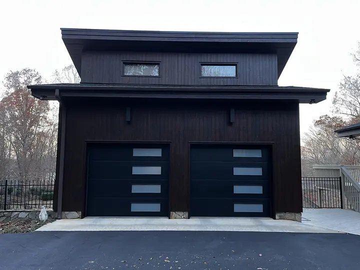 Completed Blackstone installation with black modern double garage doors on a dark exterior