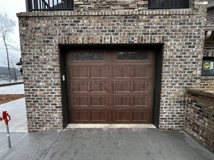 Completed Blackstone installation with a dark brown raised-panel garage door on a brick exterior